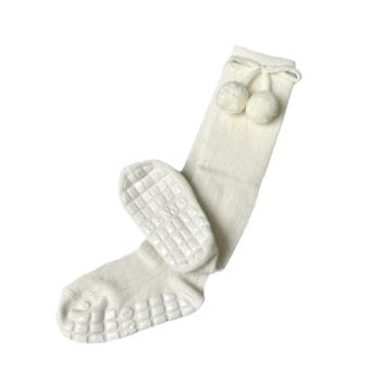 Pair of white knee-high socks with textured rubber grip soles and decorative pom-poms near the top, laid flat against a plain background.